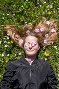 Girl lies in a flower meadow with daisies on her eyes and cherry blossoms in her hair Girl lies in a flower meadow with daisies on her eyes and cherry blossoms in her hair